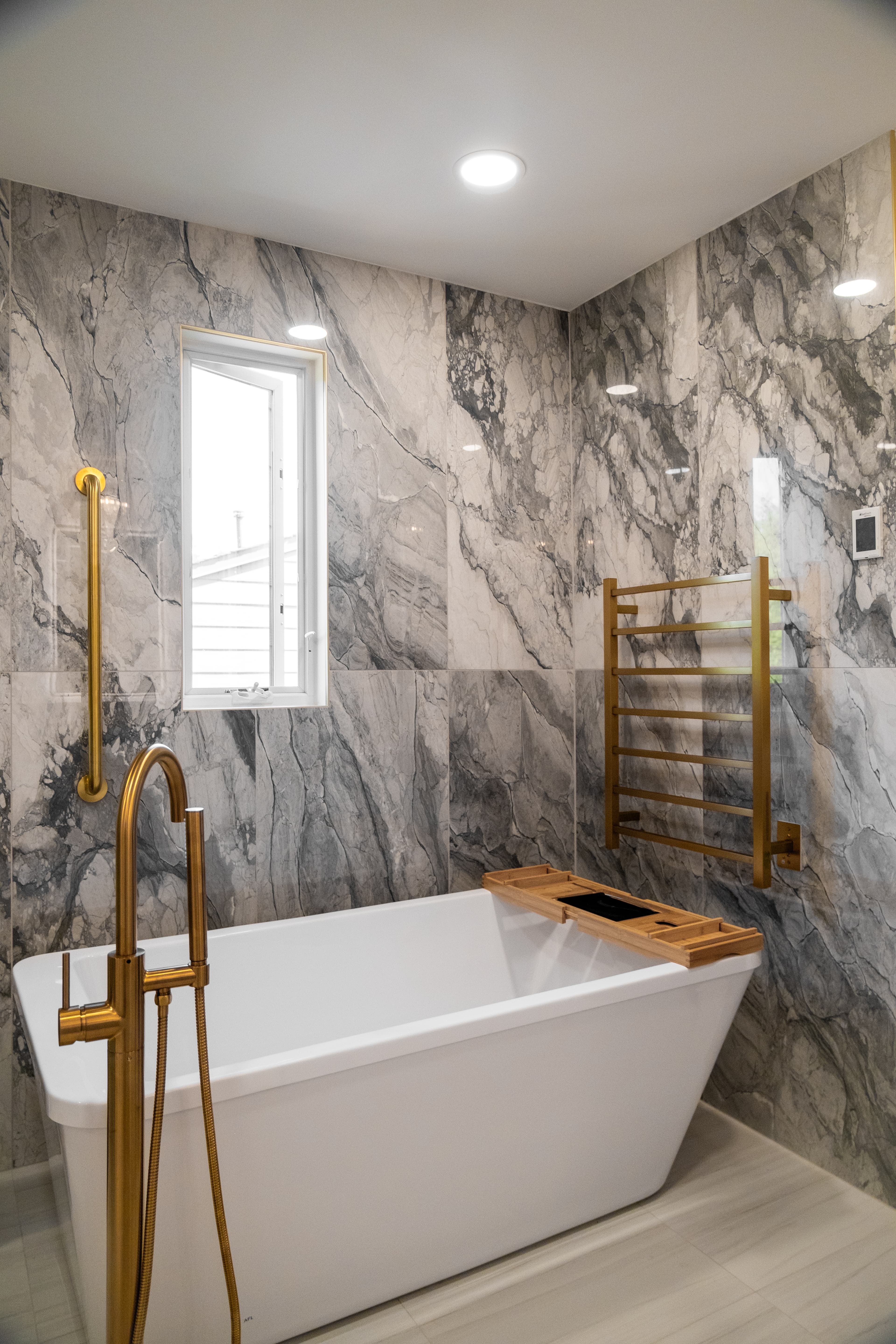 Freestanding soaking tub with marble walls and brass fixtures