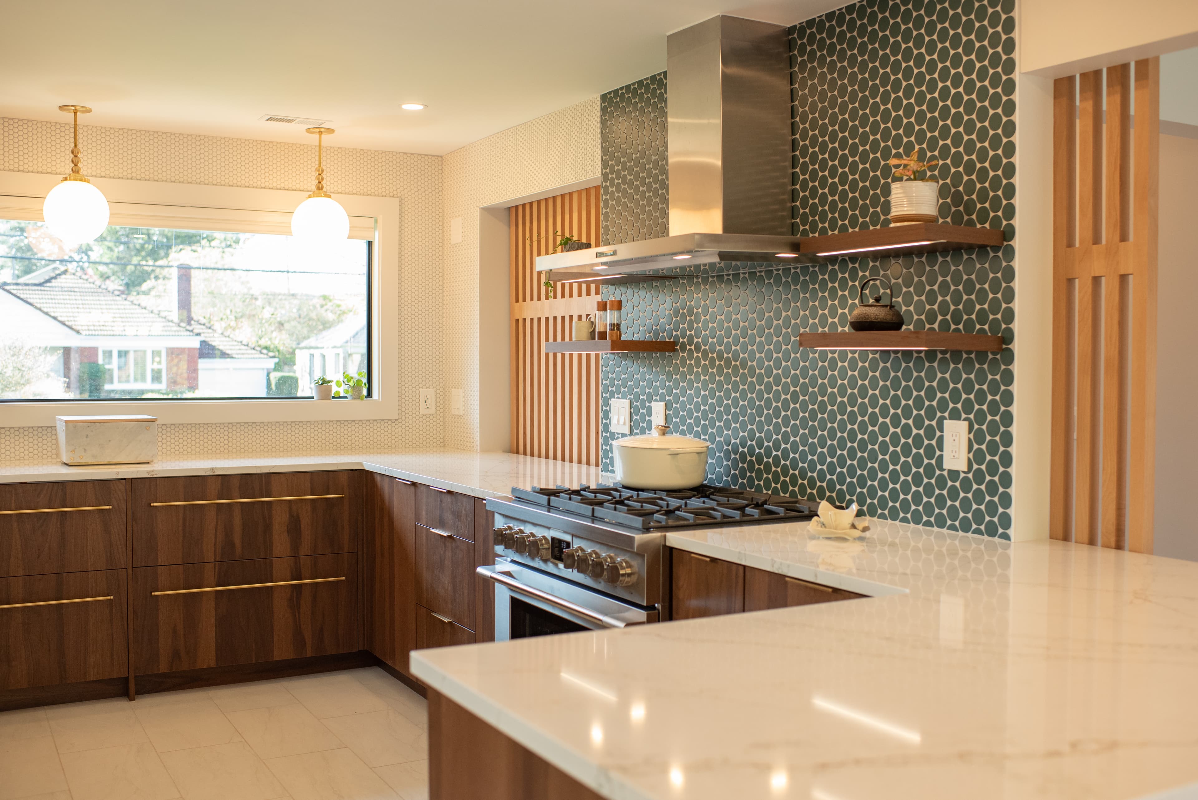 Wide view of kitchen with green tile backsplash and walnut cabinets