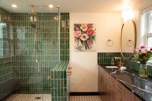 Primary bath with green tile shower and dark vanity